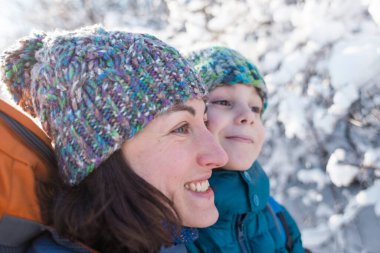 Anne oğlunu öper ve kucaklar, bir kadın kış parkında bir çocukla yürür, çocuk annesiyle, annesinin sevgisiyle vakit geçirir, karlı ormanda yürür, aile portresi çizer..