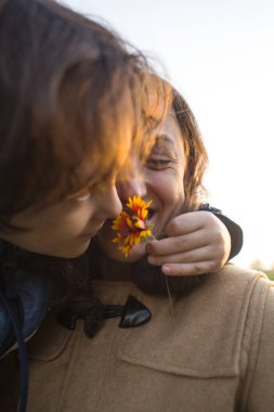 Bir çocuk annesine çiçek verir, bir çocuk annesiyle yürür, bir kadın çiçeği koklar, gülümseyen bir kadının portresi.