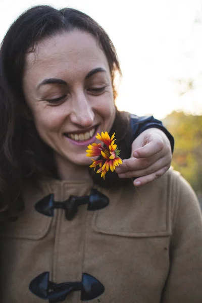 A child gives a flower to his mother, a boy walks with his mom, a woman sniffs a flower, a portrait of a smiling woman.