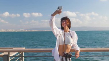 Kız blogcu sosyal ağlar için içerik çekiyor. Çekici gülümseyen turist cep telefonuyla selfie çekiyor.
