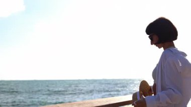 Hasır şapka takan ve okyanusa bakan bir kadın. Deniz kenarında yaz tatili. Deniz kenarında sakin ve sakin bir hayat. Özgürlük ve