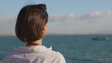 Kız setin üzerinde duran geminin fotoğrafını çekiyor. Güzel bayan turist hafta sonları dinlenirken deniz manzarasının tadını çıkarıyor. kız