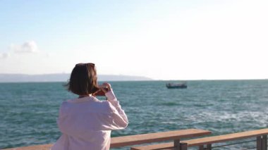 Kız setin üzerinde duran geminin fotoğrafını çekiyor. Güzel bayan turist hafta sonları dinlenirken deniz manzarasının tadını çıkarıyor. kız