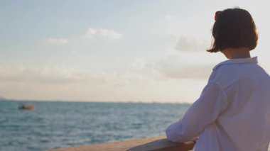 Kız setin üzerinde duran geminin fotoğrafını çekiyor. Güzel bayan turist hafta sonları dinlenirken deniz manzarasının tadını çıkarıyor. kız