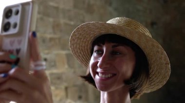 Gülümseyen neşeli bir kadın Arap ülkesinde eski bir şehrin caddesinde yürüyor. Şık gezgin şehir simgelerinin resimlerini çekiyor.