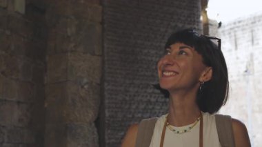 Gülümseyen neşeli bir kadın Arap ülkesinde eski bir şehrin caddesinde yürüyor. Şık gezgin şehir simgelerinin resimlerini çekiyor.