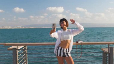 Dişi gezgin, manzaralı tahta yolda altın günbatımı selfie 'sini çekiyor. Avrupa seyahati. Yaşam tarzı, tatil, turizm, doğa, aktif