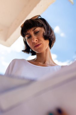 Genç bir kadın elinde zarflarla posta kutusunun önünde duruyor ve bir mektup okuyor. Posta alıcısı. Bir kız sokakta duruyor ve elinde zarflar var. Posta hizmetleri.