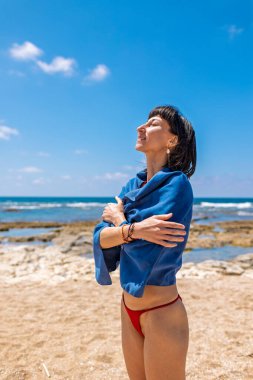 Havluya sarılmış, kumsalda eğlenen genç bir kadın. Havlu giymiş bir kız. Sahilde dinlen..