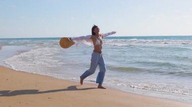 Genç ve ince esmer kumsalda tek başına yürüyor. Kumda deniz kenarında ya da okyanusta günlük kıyafetlerle yürüyen bir kız. Plaj tatili