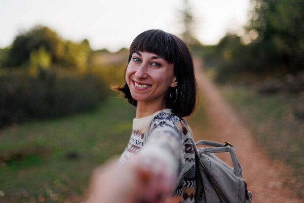 Следуйте за мной. Красивая женщина-путешественница с рюкзаком, стоящая на склоне горного хребта и держащая за руку. Пара путешественников вместе.