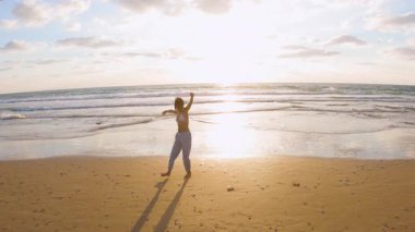 İnce bir kız gün batımında kumlu bir sahilde özgürlüğün ve aşkın tadını çıkartıyor. Romantik bir hava..