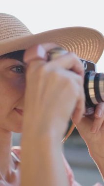 Dikey çekim. Modern çağdan bir kadının portresi seyahat blogcusu analog bir kamerayla turistlerin ilgisini çekiyor. Gülümse.