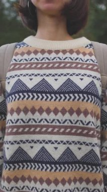 Dikey çekim. Sırt çantalı bir kız kameraya bakar ve gülümser. Doğanın tadını çıkaran ve romantik bir ruh hali içinde bir kadın. Ona yakın çekim.