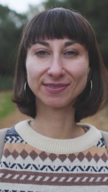 Dikey çekim. Bir kız kameraya bakar ve gülümser. Bir kadın doğayı ve romantik havayı sever. Yüzüne yakın çekim. Birlikte bir kız