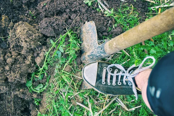 穿旧运动鞋的女性脚夏天在花园里用铁锹挖泥土 — 图库照片