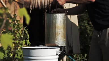 Sadece bir kuyuya bir kova bir yaz günü kırsal alınan bir adam taze su dökerek yavaş çekim