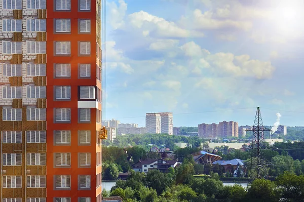 Московский городской пейзаж с рабочим в строительной колыбели на стене строящегося здания, освещенного солнечными лучами — стоковое фото