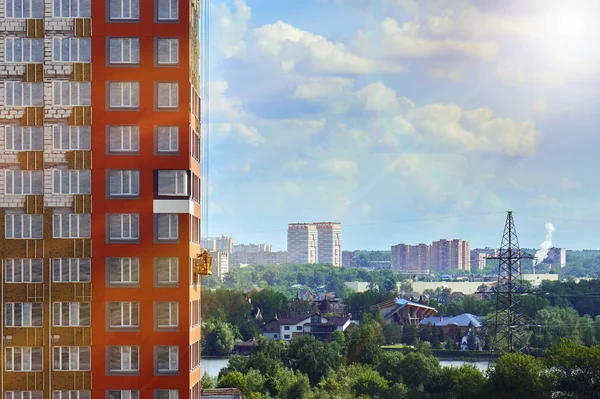 Moscovo paisagem urbana com um trabalhador em um berço de construção na parede de um edifício em construção iluminado por raios de sol — Fotografia de Stock