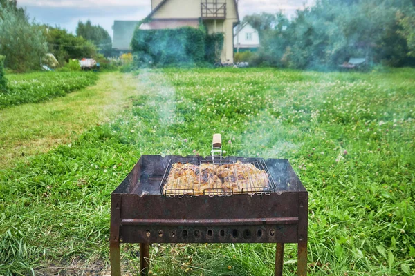 Preparing a chiken in a suburban area using a chairgrill and grill grid outdoors — Stock Photo, Image