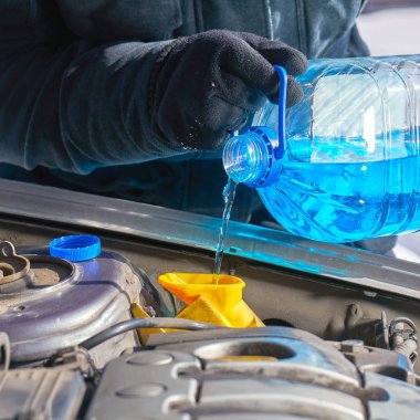 Adam bir araba bir ön cam yıkama deposu tarafından antifriz doldurma