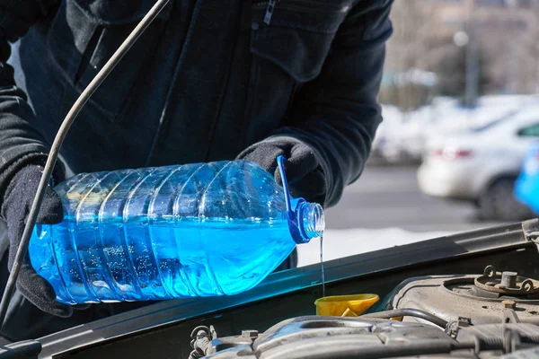 Mann füllt Scheibenwaschbecken eines Autos mit Frostschutzmittel — Stockfoto