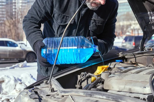 Mann füllt Scheibenwaschbecken eines Autos mit Frostschutzmittel — Stockfoto