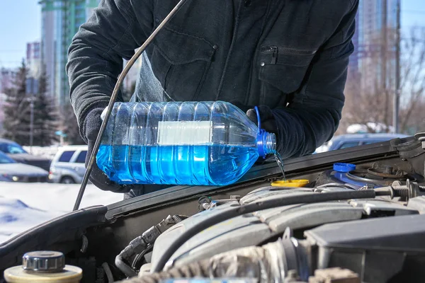 Muž plnění nádrže pračka čelní sklo automobilu o nemrznoucí zimní moskevské ulici — Stock fotografie