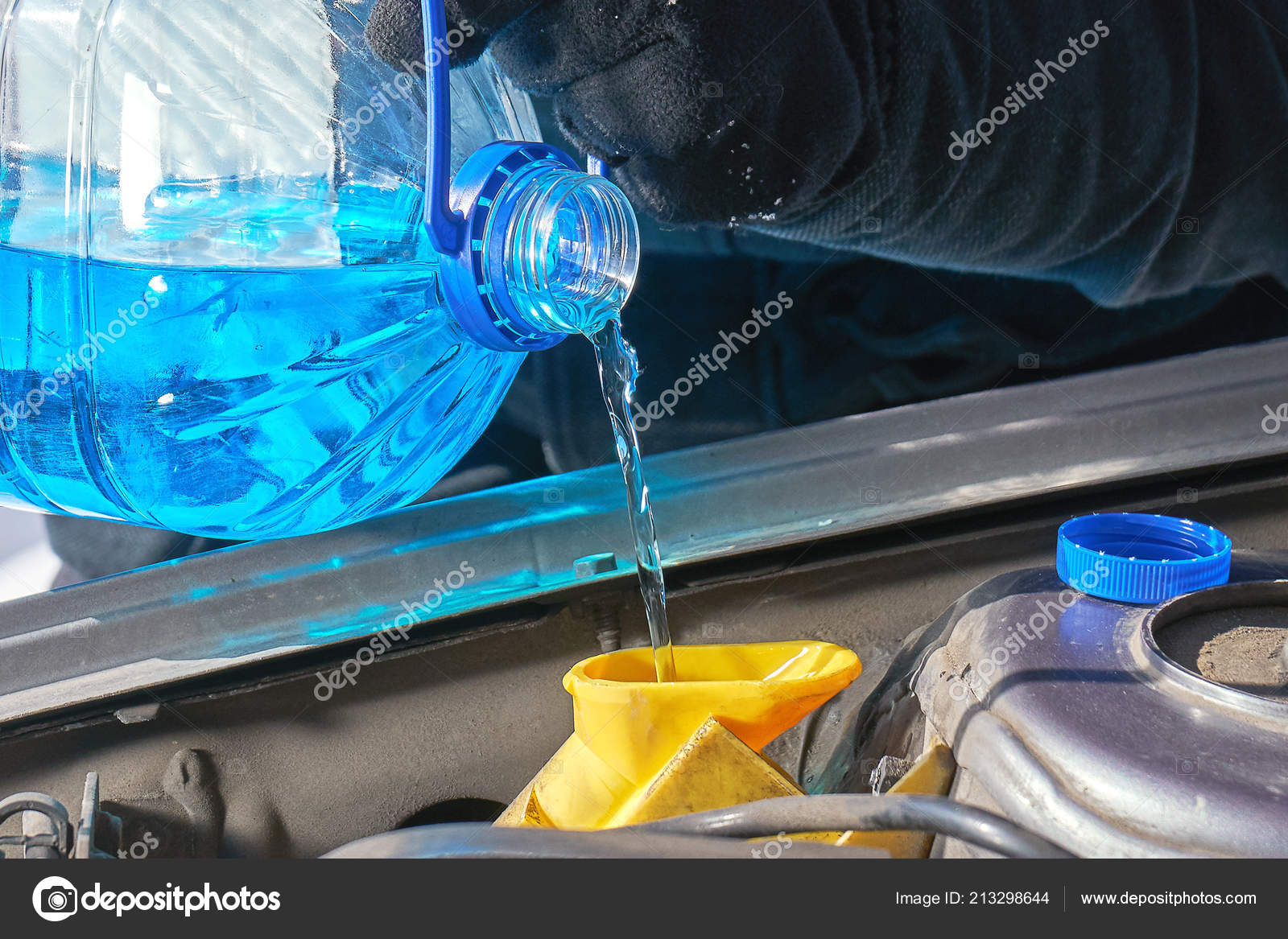 Filling a windshield washer tank of a car with a wiper fluid outdoors ⬇