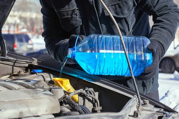 Muž plnění nádrže pračka čelní sklo automobilu na ulici v zimě — Stock fotografie