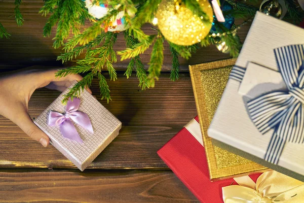 Girl\'s hand picks up or puts a little gift box from under a Christmas tree in New Year