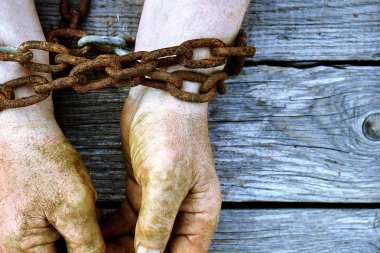 Eski paslı kalın zincirli bir kopya alanı ile ahşap kurullarında zincirli kirli eller erkek. Unfreedom kavramı.