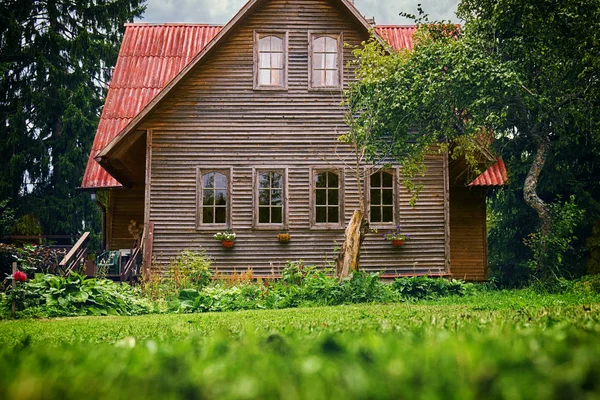 Vooraanzicht van een voorstedelijke huis met rood dak en groene tuin in de zomer — Stockfoto