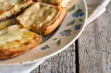 Ahşap kurullarında eski bir tabak içinde erimiş peynirli tost yakın çekim