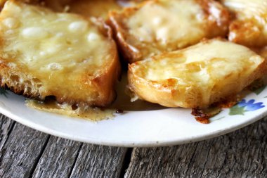 Ahşap kurullarında eski bir tabak içinde erimiş peynirli tost