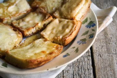 Ahşap kurullarında eski bir tabak içinde erimiş peynirli tost
