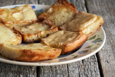 Ahşap kurullarında eski bir tabak içinde erimiş peynirli tost