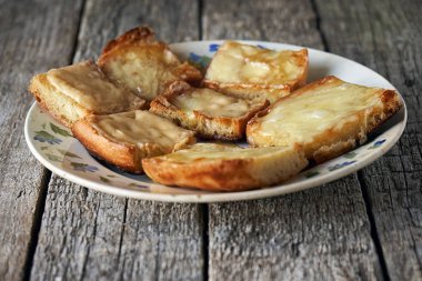 Ahşap kurullarında eski bir tabak içinde erimiş peynirli tost