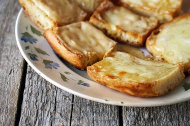 Ahşap kurullarında eski bir tabak içinde erimiş peynirli tost