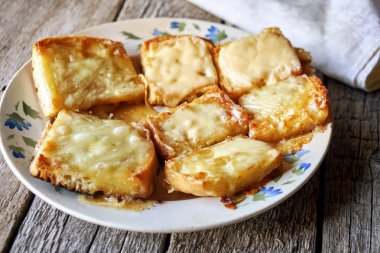 Ahşap kurullarında eski bir tabak içinde erimiş peynirli tost