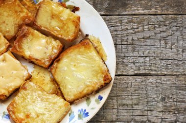 Ahşap kurullarında eski bir tabak içinde erimiş peynirli tost. Düz yatıyordu