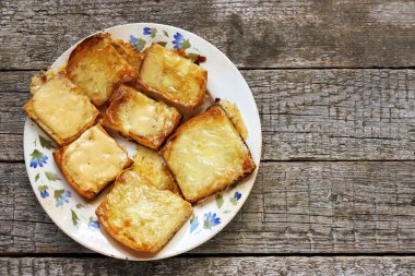 Ahşap kurullarında eski bir tabak içinde erimiş peynirli tost. Düz yatıyordu