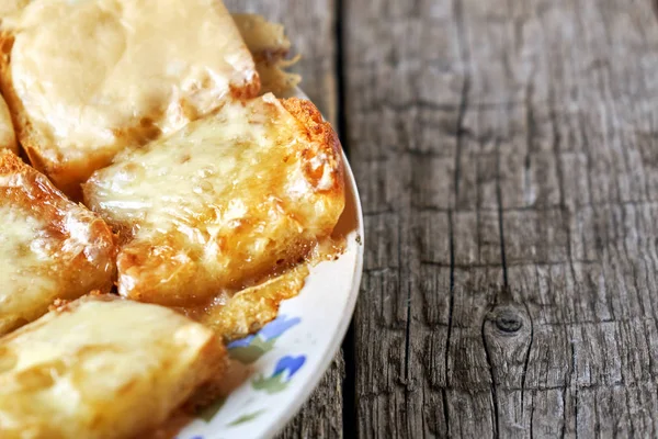 Ahşap kurullarında eski bir tabak içinde erimiş peynirli tost