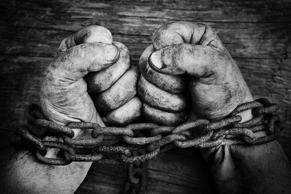 Powerful dirty male hands clenched into fists chained with rusty chain. Black and white photo. — Stock Photo, Image