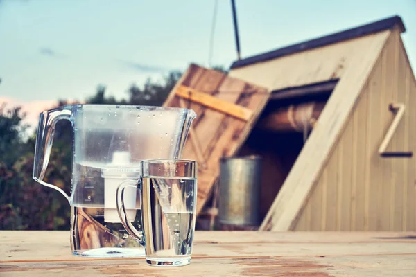 在夏季傍晚 在乡村的户外 水过滤罐和一杯透明的干净水玻璃 — 图库照片