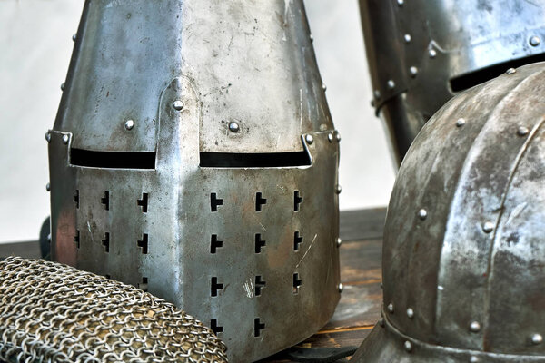 Steel medieval helmets with eyes slits standing on the wooden table