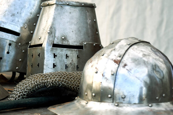 Steel medieval helmets with eyes slits standing on the table