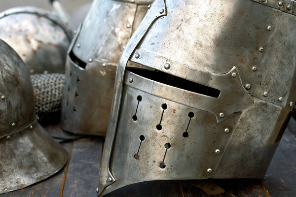 Steel medieval helmets with eyes slits standing on the wooden table