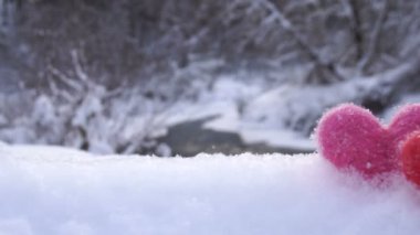 Kışın nehir kıyısında beyaz kar kırmızı ve pembe yün kalpler
