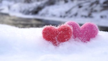 Kışın nehir kıyısında beyaz kar kırmızı ve pembe yün kalpler